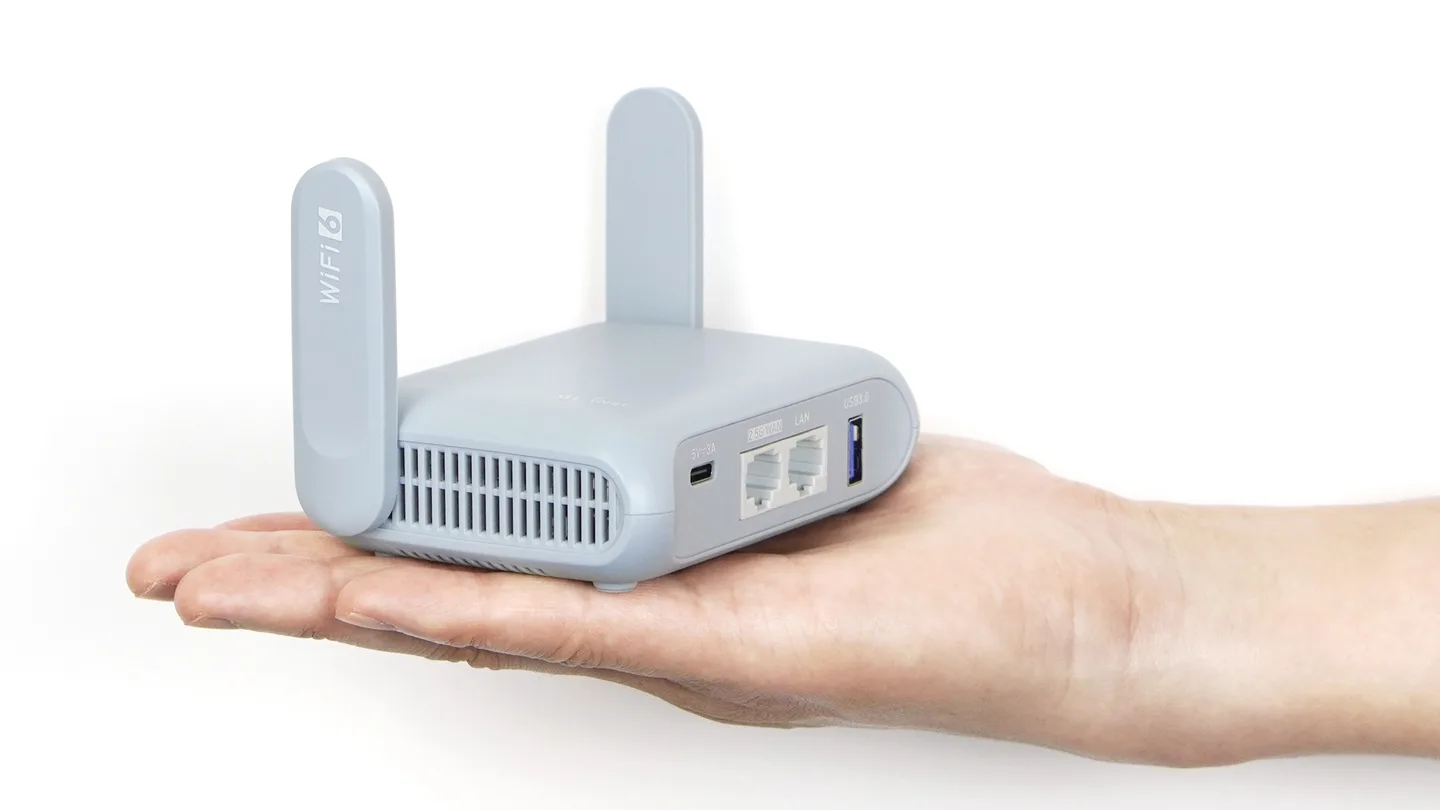 Um roteador de viagem GL.iNet Beryl AX, o Spun Box, segurado em uma mão